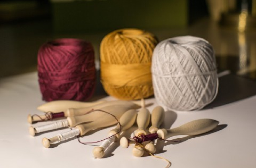 Narzędzia do koronki klockowej - klocki i trzy szpule nici: biała, żółta i bordowa.