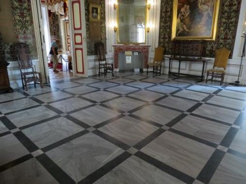 Kolorowe zdjęcie. Przedstawia salę w pałacu. Na ścianach znajdują się obrazy olejne i lustro. Posadzka kamienna, dwukolorowa.